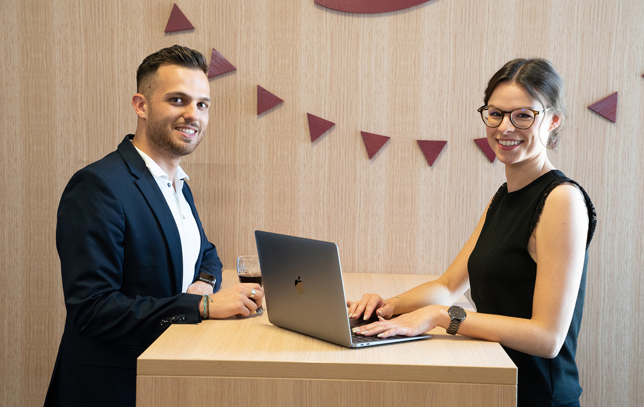 Zwei Mitarbeiter:innen vor einem Laptop