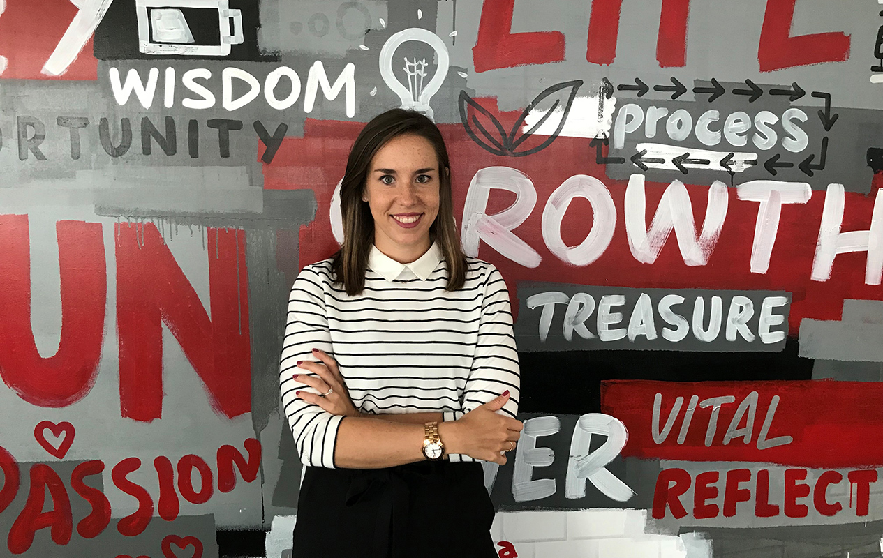 Junge Frau mit verschränkten Armen, die in die Kamera lacht