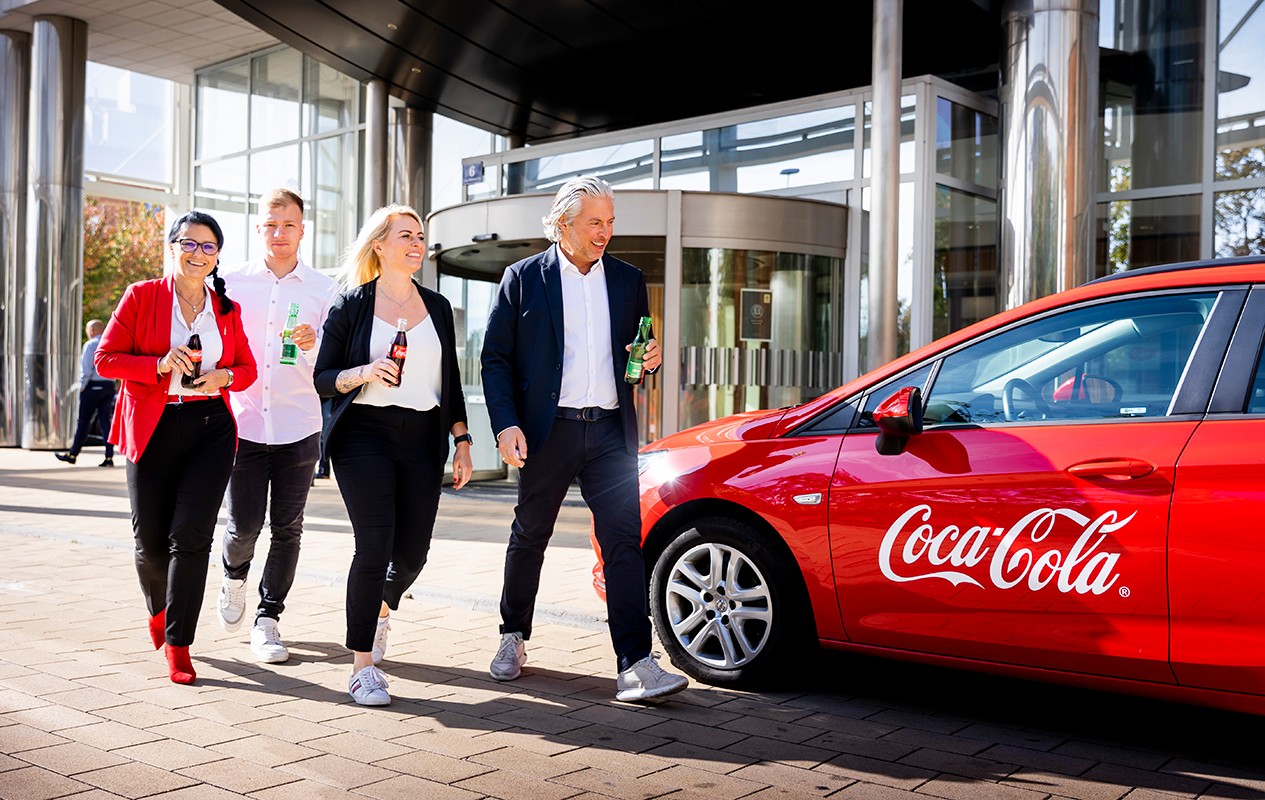 Four employees next to a red Coca-Cola car