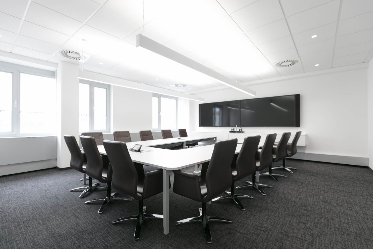 Meeting room with 13 black office chairs and a large screen.